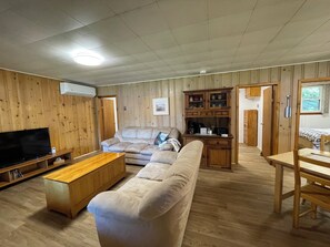 Een woonkamer met een bank, een salontafel, een televisie en een kast.