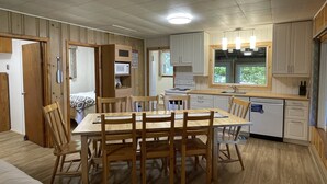 Una cocina compacta con armarios de madera, una mesa de comedor con sillas, un microondas y un lavavajillas.