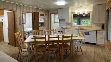 Une cuisine compacte avec des meubles en bois, une table à manger avec des chaises, un four à micro-ondes et un lave-vaisselle.