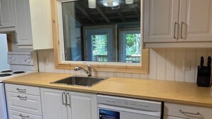Una cocina con armarios blancos, encimera de madera, lavavajillas integrado y luces colgantes.