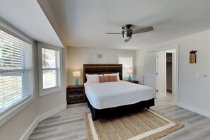A bedroom with a large bed, a ceiling fan, and a view through the window. - Turtle Dove (Panama City Beach)