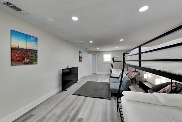 A modern room with bunk beds, a flat-screen TV, a sofa, and a painting on the wall. - Turtle Dove (Panama City Beach)