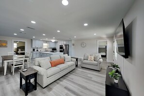 A modern living room with a sofa, a coffee table, and a TV mounted on the wall. - Turtle Dove (Panama City Beach)