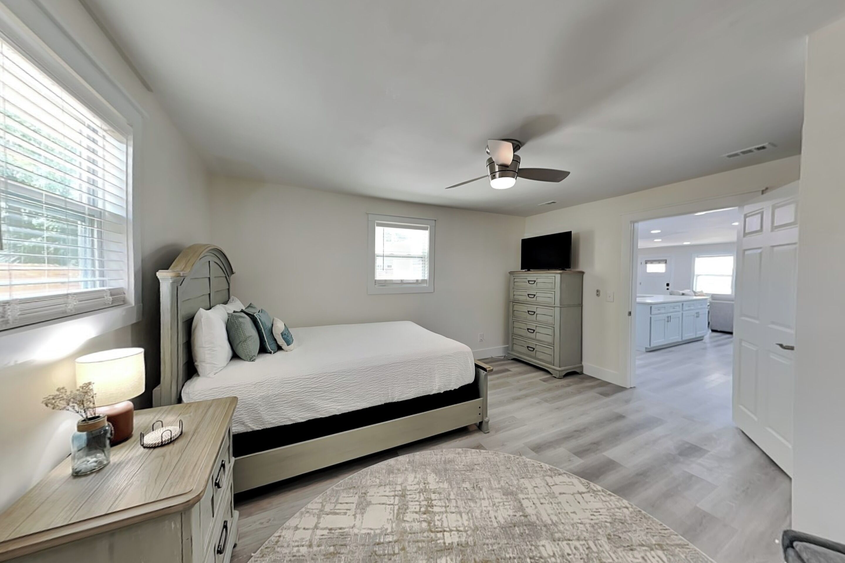 Un dormitorio con cama, cómoda y ventilador de techo.