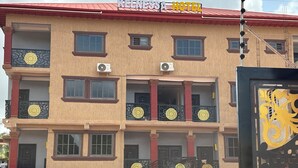 Un hotel de varios pisos con balcones, unidades de aire acondicionado y techo rojo.