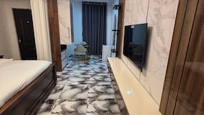A hotel room with a bed, a TV, a desk, and a bathroom.