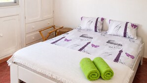 A neatly made bed with a white and purple bedspread, two pillows, and two green towels. - Plage Blue Lagoon | Ocean View Penthouse (Mbour)