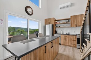 Eine moderne Küche mit Kochinsel, Holzschränken und Blick ins Freie.