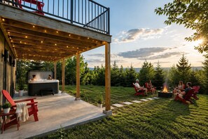 Eine überdachte Terrasse im Freien mit Whirlpool, roten Stühlen und einem Feuerkorb.