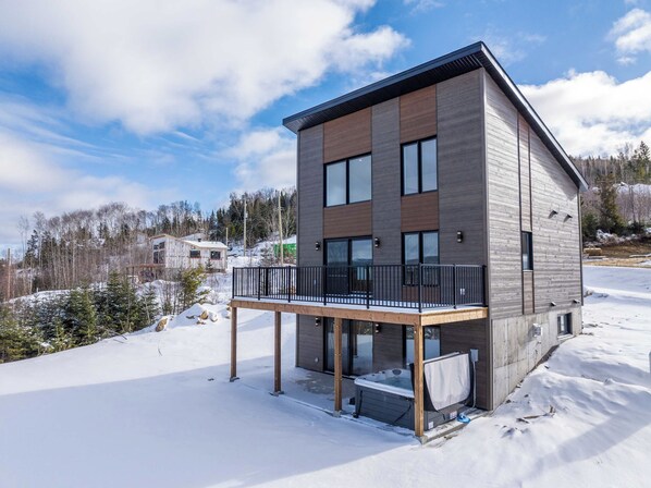 A modern two-story building with a balcony, surrounded by snow and trees. - Apex Nuage - Spa, Game Room & Panoramic Views (Saint-Côme)