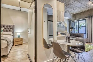 Quarto moderno com cama, mesa de cabeceira e espelho.