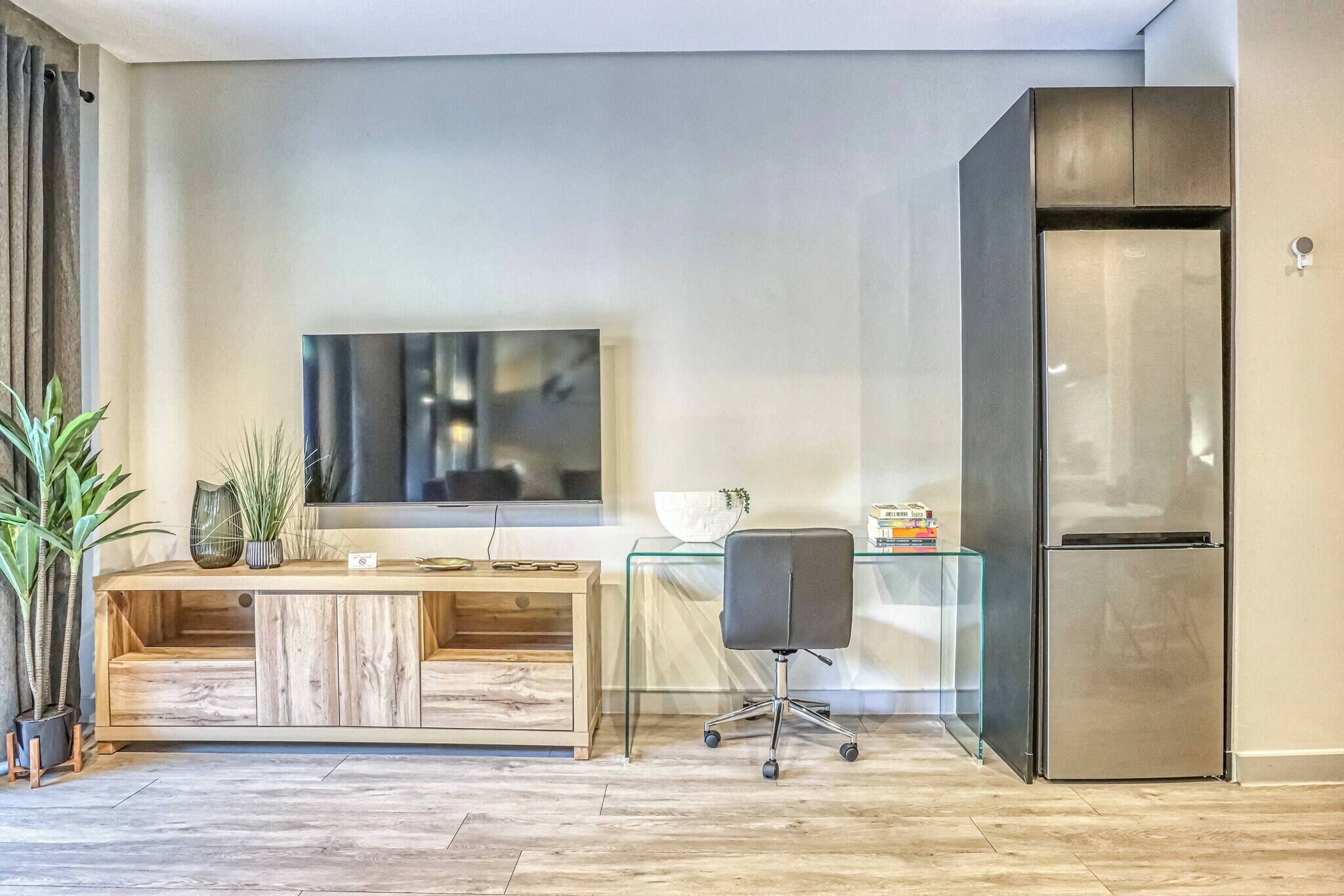 Una cocina moderna con refrigerador empotrado, una mesa de comedor de madera y una mesa de centro de vidrio.