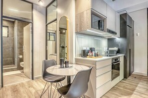 Cozinha moderna com micro-ondas, fogão e pia. Possui uma área de jantar com mesa e cadeiras.