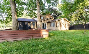 A residential property with a wooden deck, a fenced yard, and a house with a chimney.