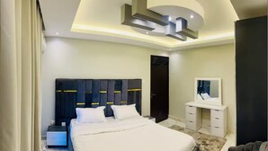 Une chambre à coucher moderne avec un grand lit, une table de chevet, une commode, un miroir et un design de plafond original.