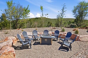Een terras met Adirondack-stoelen en een vuurkorf.