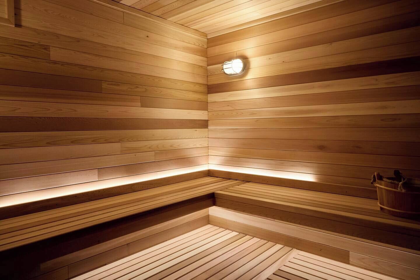Una sauna de madera con un banco y una lámpara.