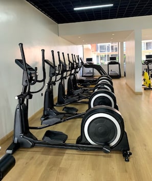Ett gym med flera konditionsträningsmaskiner uppställda i en rad.