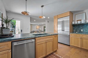 Eine moderne Küche mit Edelstahlgeräten, Holzschränken und einer Arbeitsplatte aus Granit.