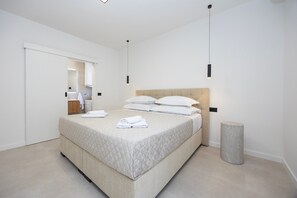 Ein modernes Schlafzimmer mit einem Bett, einem Nachttisch, einer Lampe und einem Spiegel.