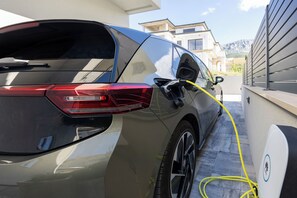 A car parked in a driveway with a charging cable connected to it. - Holiday home JOlive (Kaštel Gomilica)
