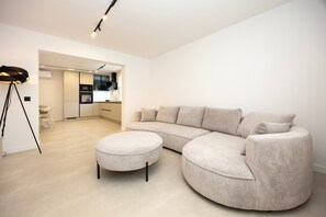 A modern living room with a sectional sofa, a round ottoman, and a floor lamp. - Holiday home JOlive (Kaštel Gomilica)