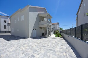 Ein modernes Gebäude mit flachem Dach, einem Balkon und einem gepflasterten Innenhof.