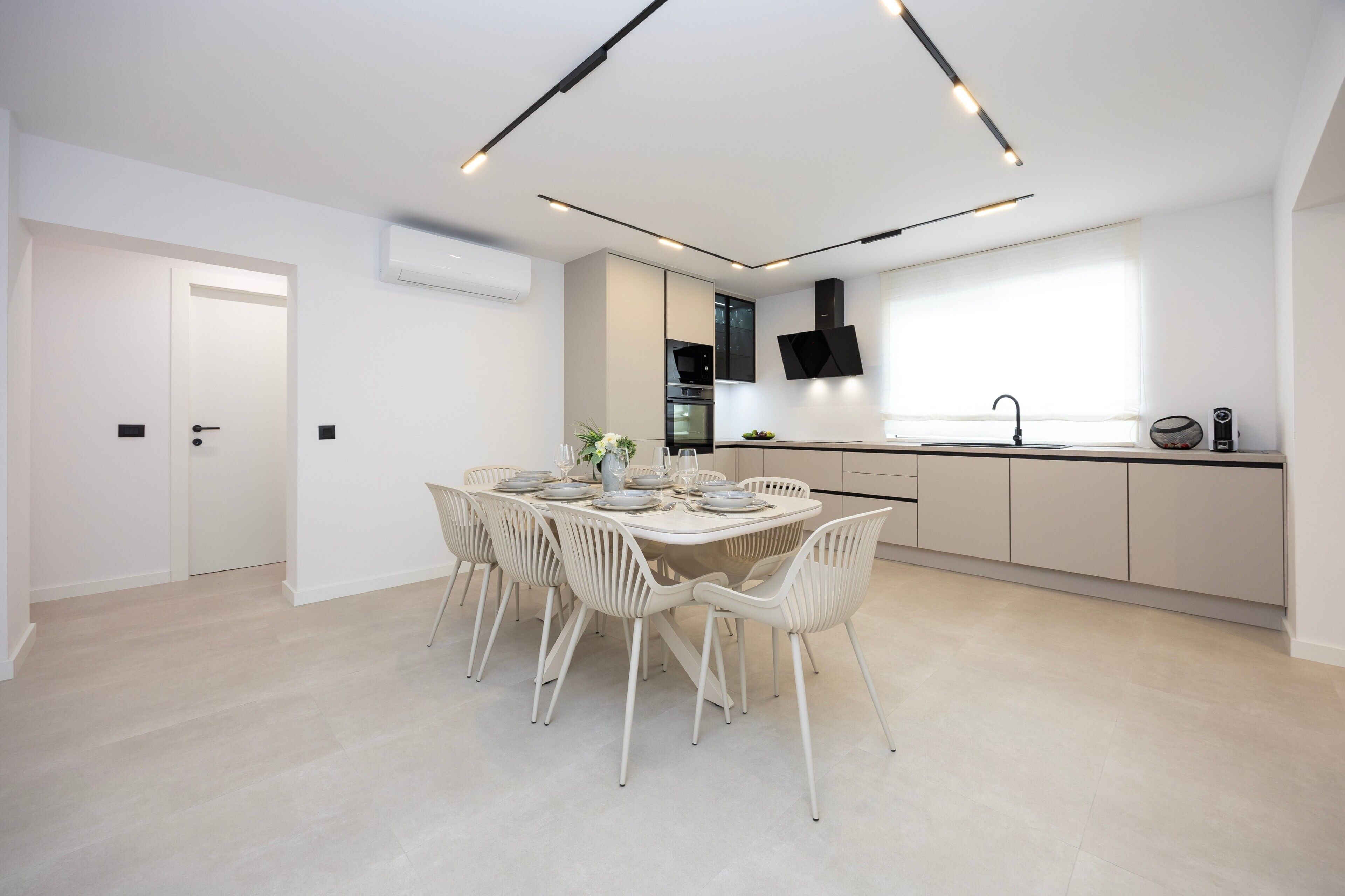 Een moderne keuken met een eethoek, witte kastjes en een inbouwoven.
