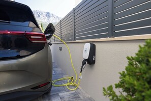 Um carro estacionado em uma estação de carregamento de veículos elétricos, com um cabo conectado.