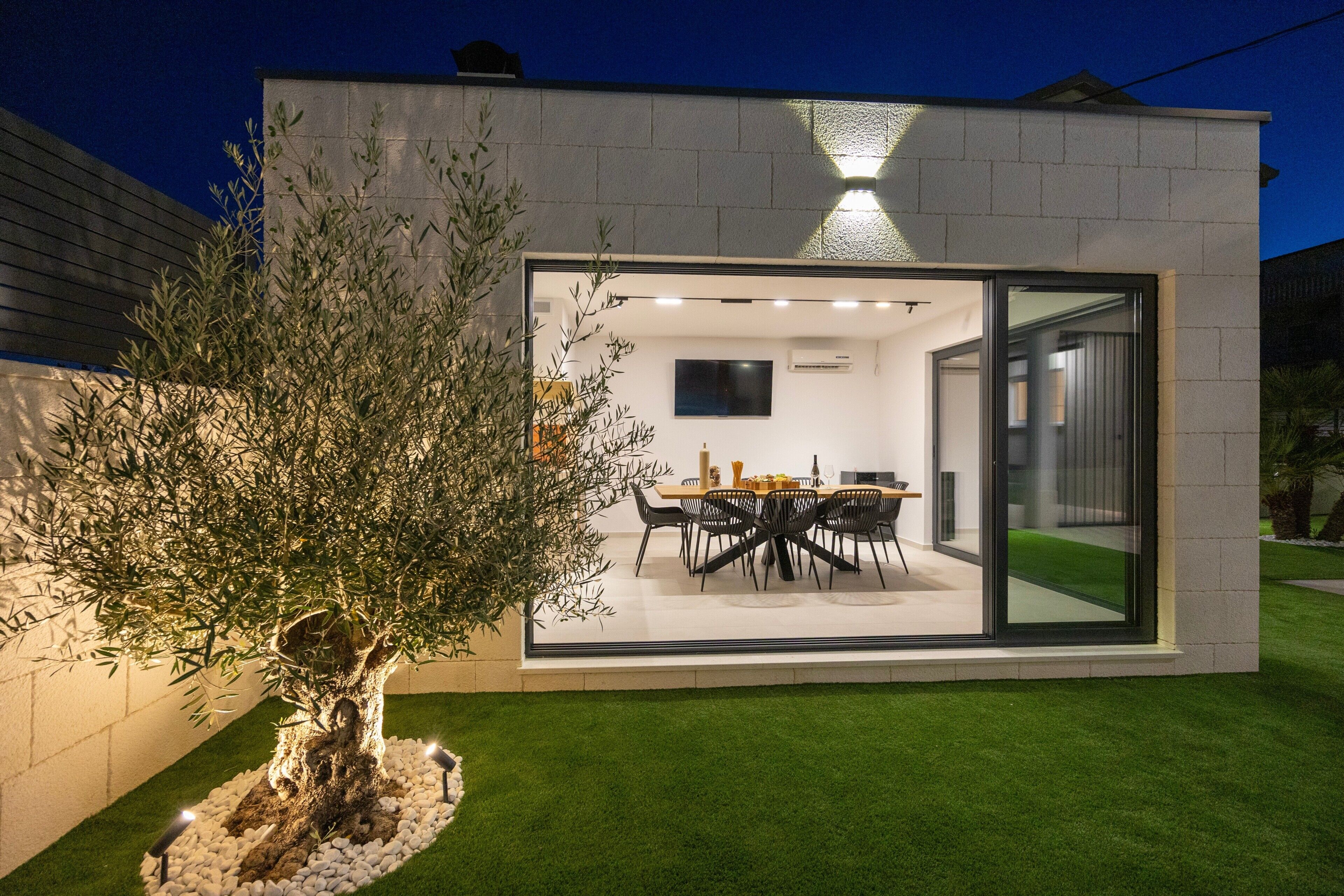 A modern house with a dining area, a TV, and a large window.