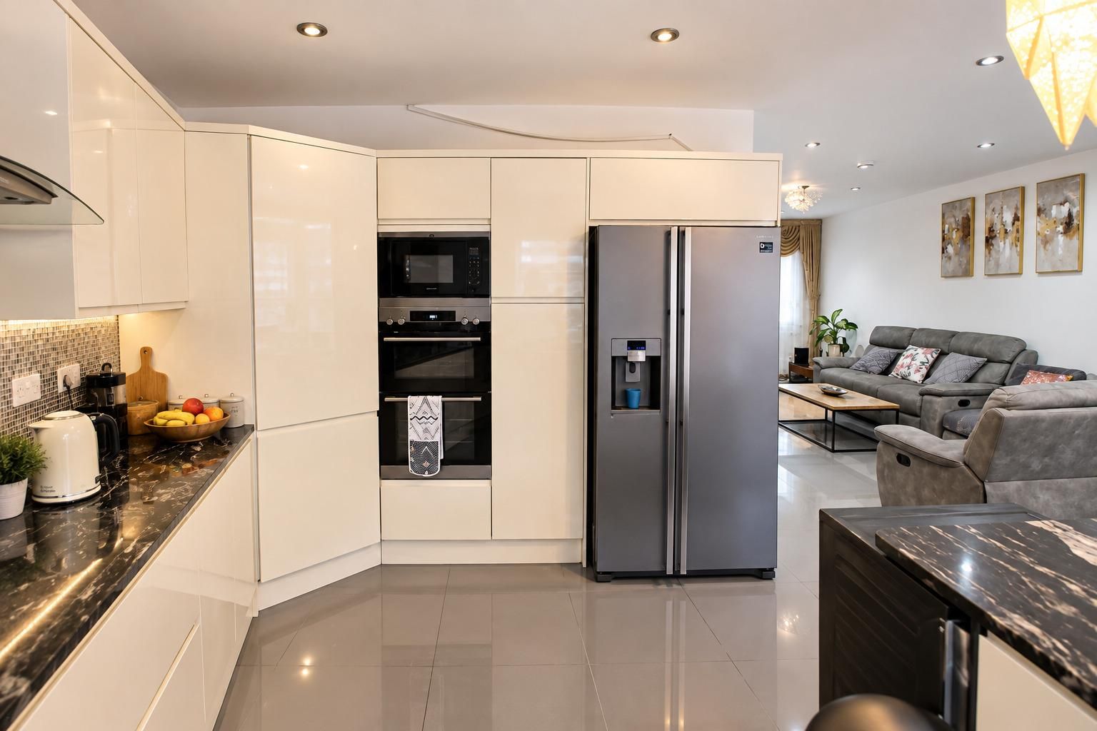 A modern kitchen with a built-in oven, a refrigerator, and a coffee machine.
