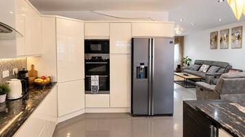 A modern kitchen with a built-in oven, a refrigerator, and a coffee machine.