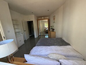 Un dormitorio con cama, cómoda, espejo y puerta que da a un baño.