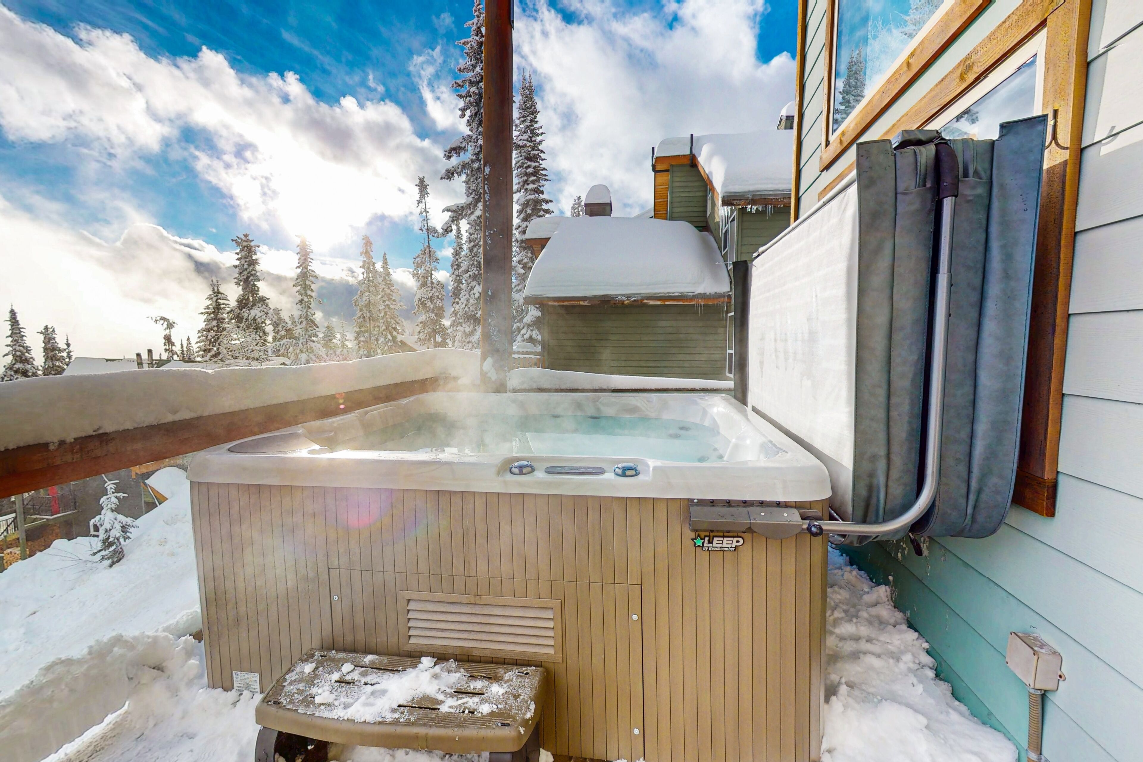 A hot tub outside a building with snow on the ground and trees in the background.