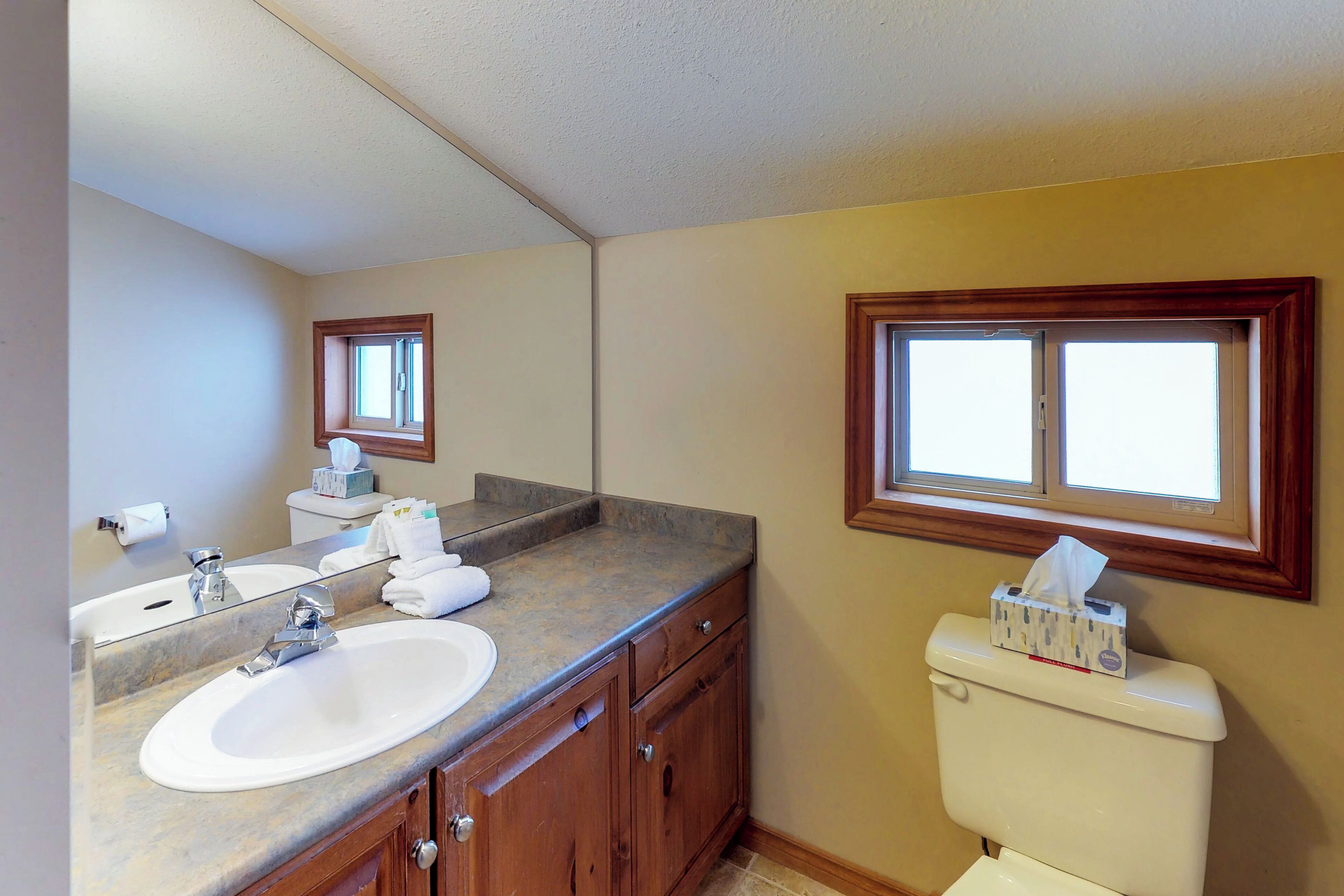 A bathroom with a sink, mirror, and toilet.