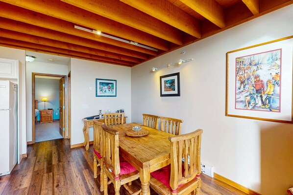A dining area with a wooden table and chairs, a hallway leading to another room, and framed pictures on the walls. - Arolla Chalet by Okanagan Premier (Beaverdell)