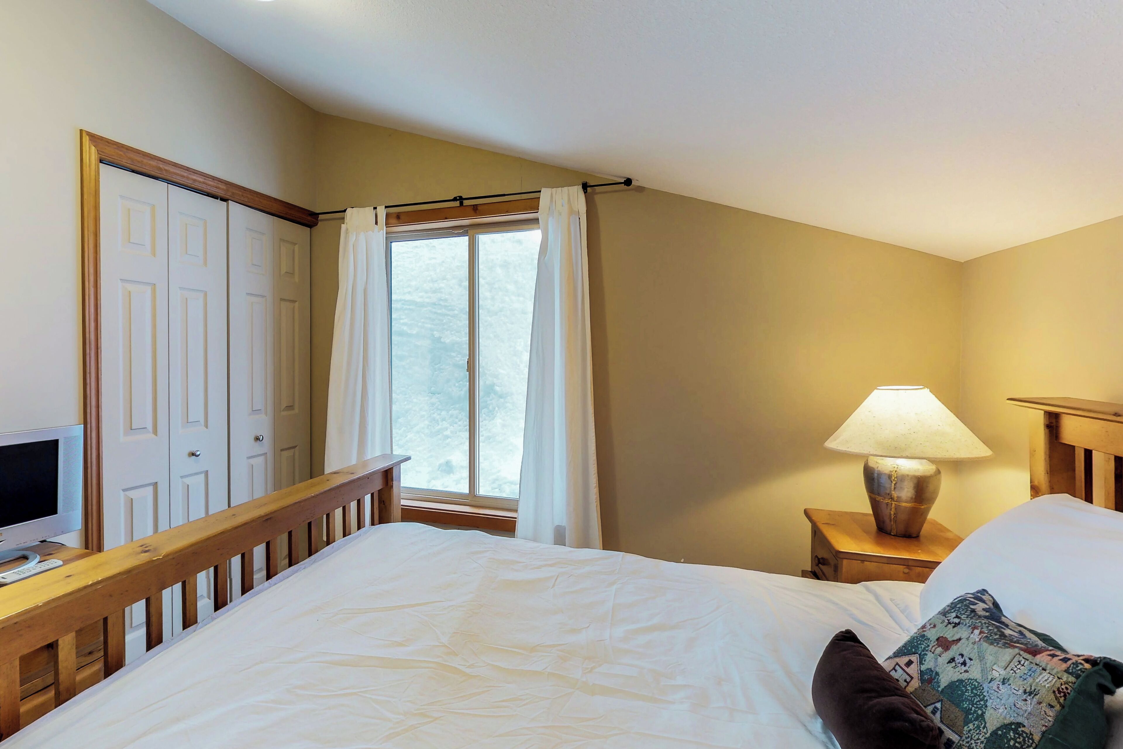 Una camera da letto con un letto, un comodino con una lampada, una finestra con tende e un armadio.