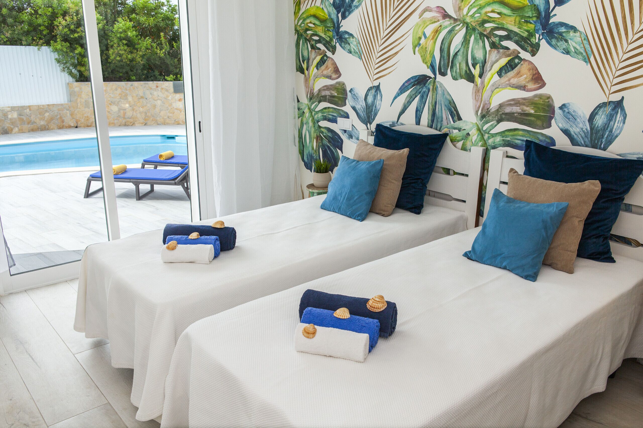 Una habitación con dos camas, piscina y decoración temática tropical.