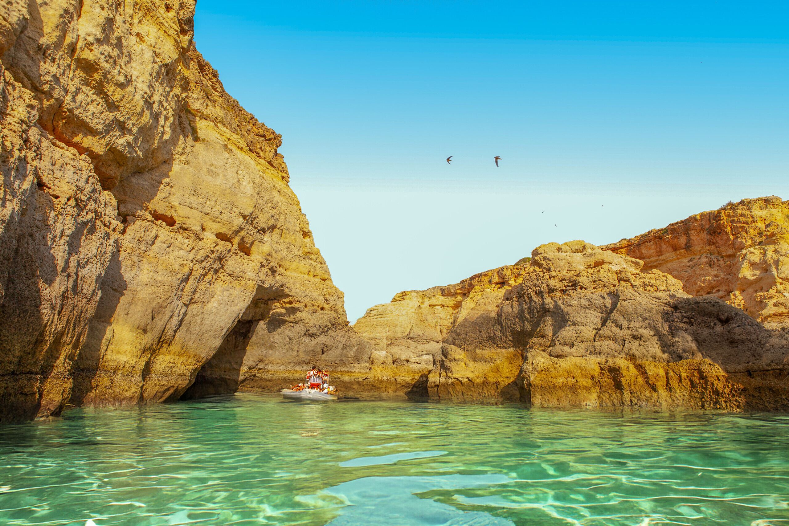 A boat in a rocky cove with clear turquoise water.