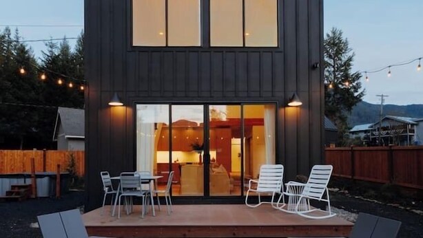 Uma casa moderna com deck, área de estar externa e lareira.