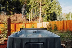 Een jacuzzi in een achtertuin met een houten schutting en bomen.