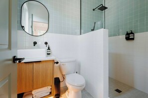 Een badkamer met toilet, wastafel, spiegel en douche.