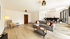 Un salon comprenant un canapé, une table basse, une lampe, ainsi qu’un coin repas avec des chaises et une table.