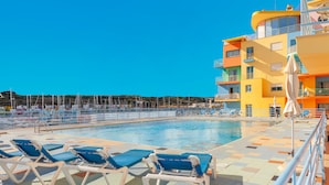 Zona de piscina con tumbonas y vistas a un edificio de colores.