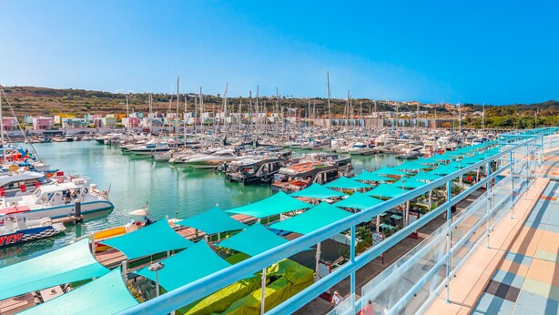 Un port de plaisance où sont amarrés de nombreux bateaux, un ciel dégagé et une vue sur le paysage environnant.