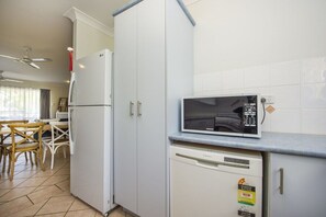 Eine kleine Küche mit weißen Schränken, einer Mikrowelle und einem Geschirrspüler.