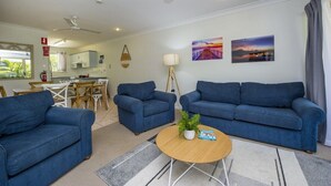 A living room with a blue sofa set, a coffee table, and a dining area with a table and chairs.