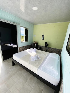 A hotel room with a bed, a window, a small table, and a wall-mounted picture. - Macori Cabañas Campestres (Rivera)