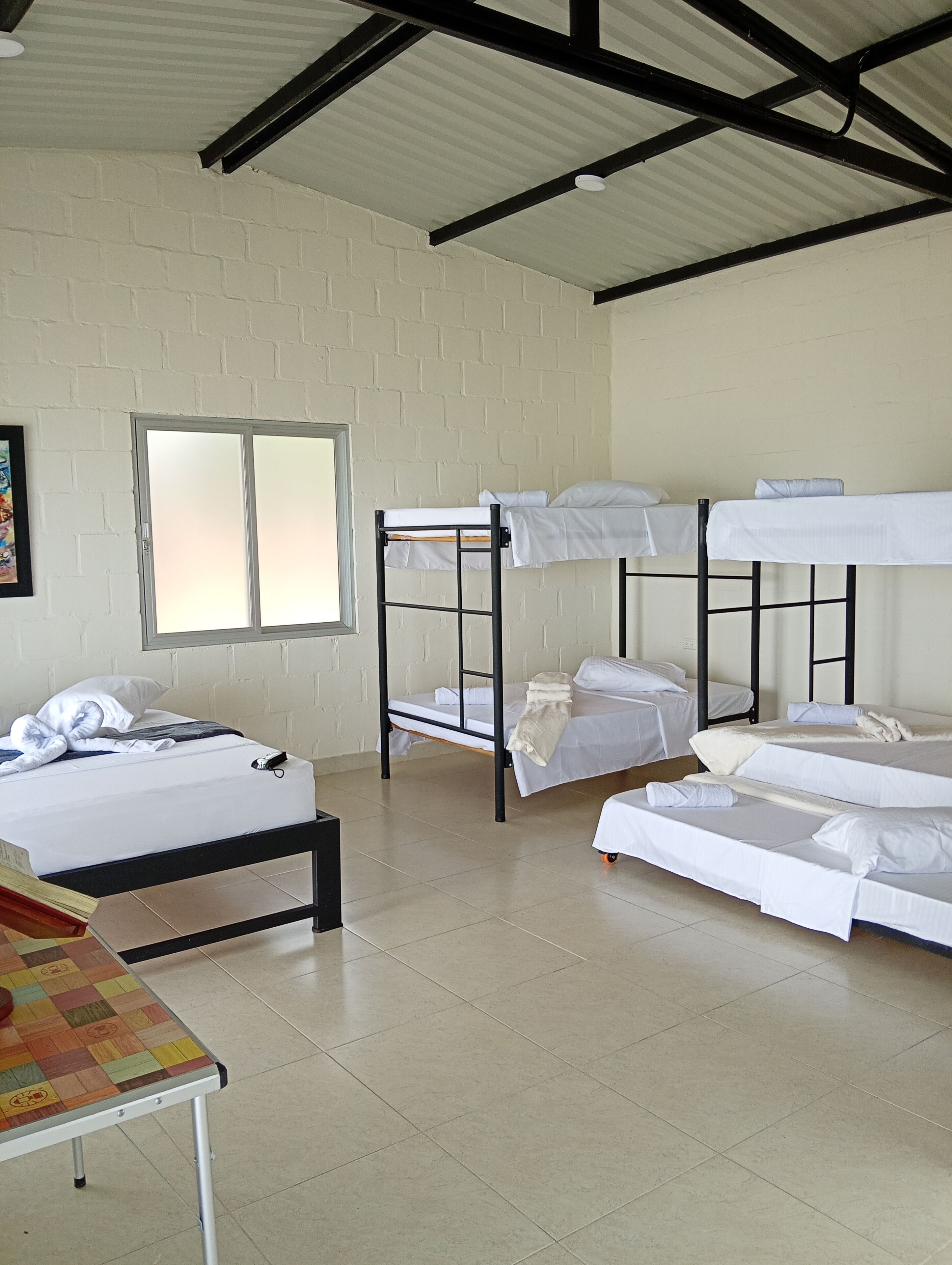 A dormitory room with bunk beds, a window, and a table.