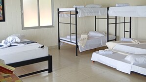 A dormitory room with bunk beds, a window, and a table. - Macori Cabañas Campestres (Rivera)